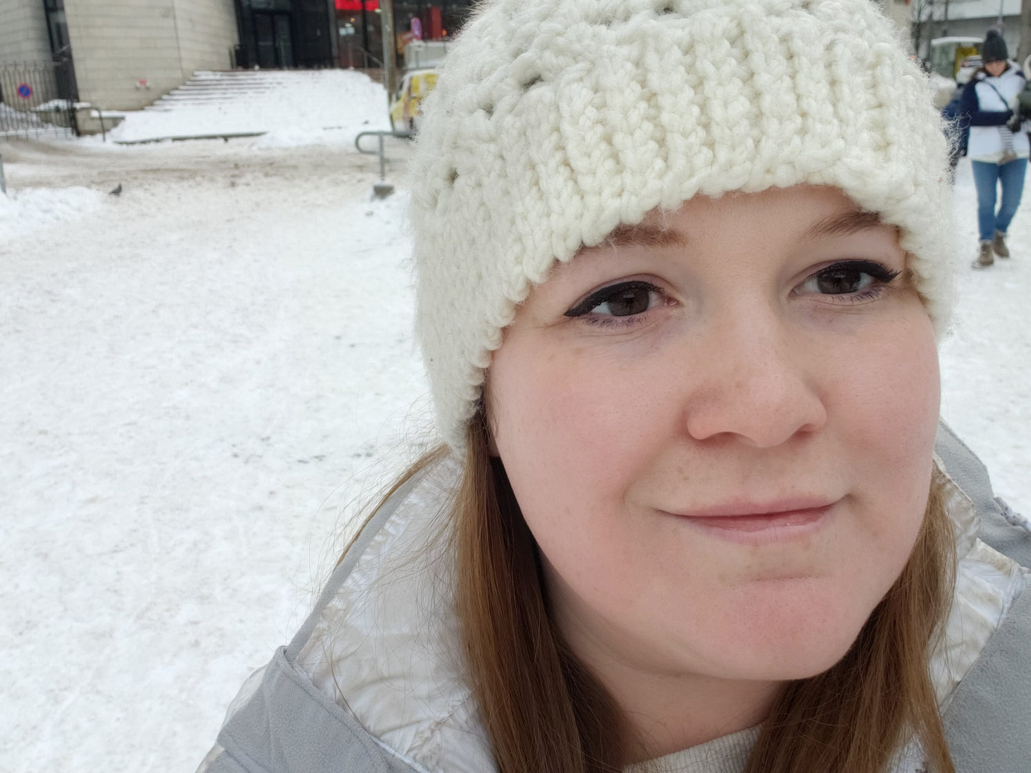 Woman wearing a white knit beanie in a snowy outdoor setting